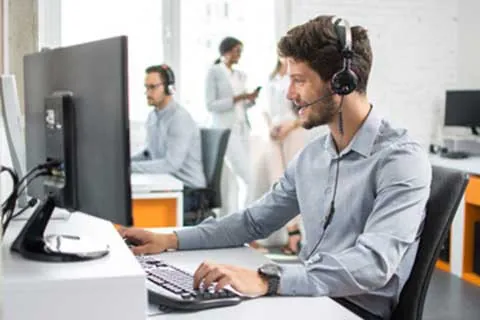 Technicien du support informatique avec casque, devant son écran